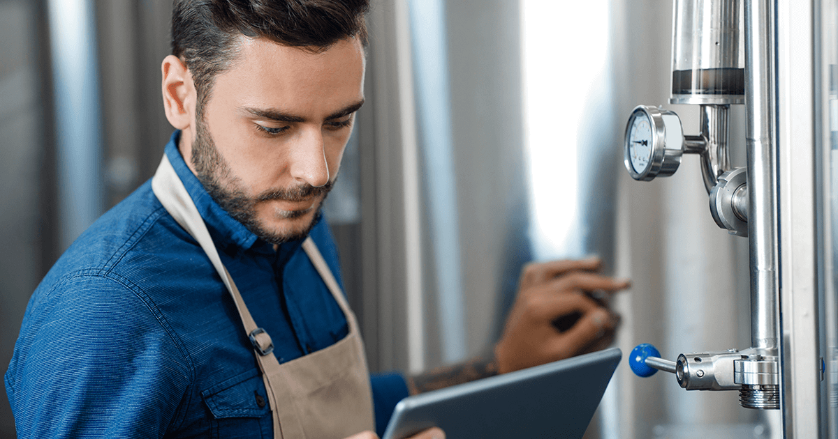 Retrato do trabalhador da cervejaria verificando o processo de fermentação, tecnologia e aplicativo para pequenas empresas